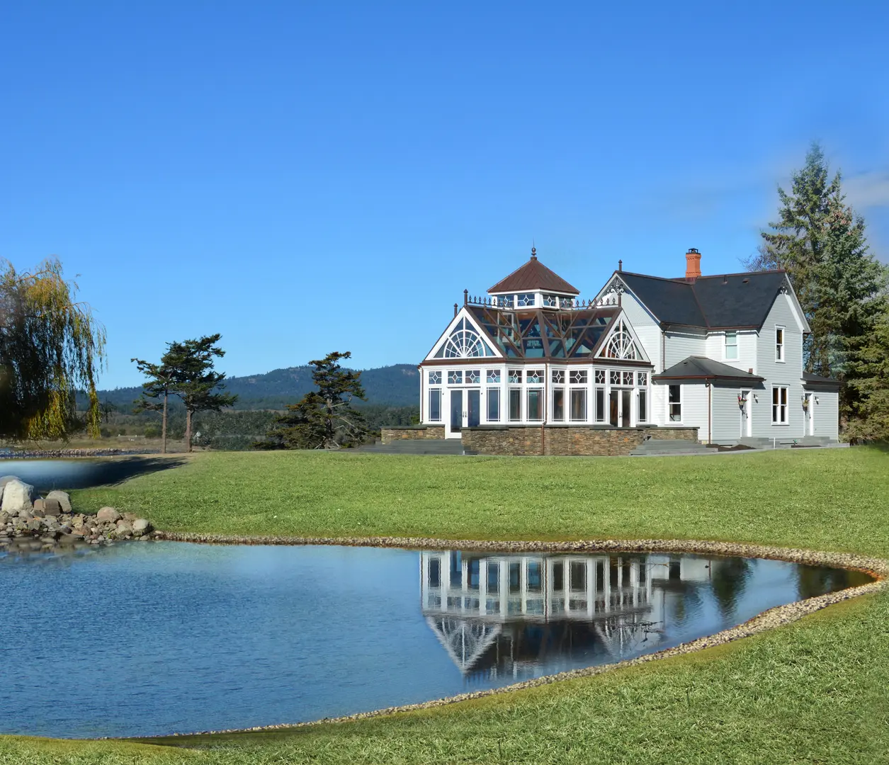 A large white house sitting next to a pond.