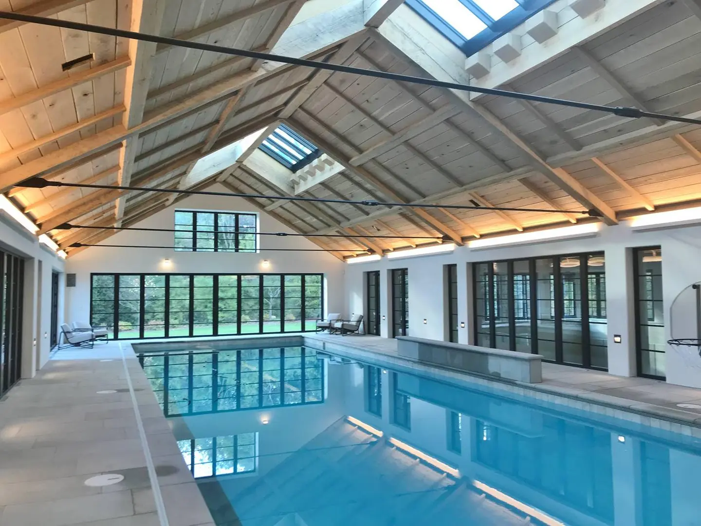A large indoor swimming pool with skylights and a glass wall.