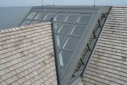 A roof with a skylight and a wooden shingle roof.