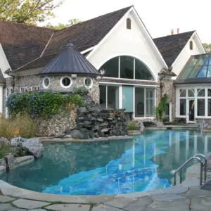 A pool with a waterfall and a house