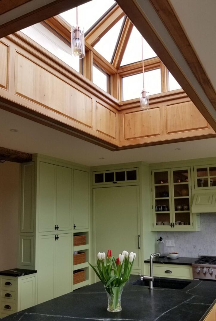 A kitchen with green cabinets and a skylight.