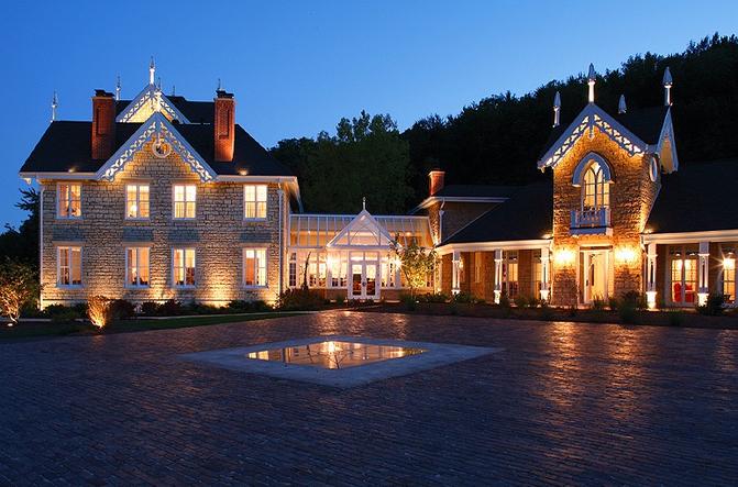 A large mansion with lights on the outside of it.