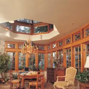 A dining room with a table and chairs, chandelier and windows.