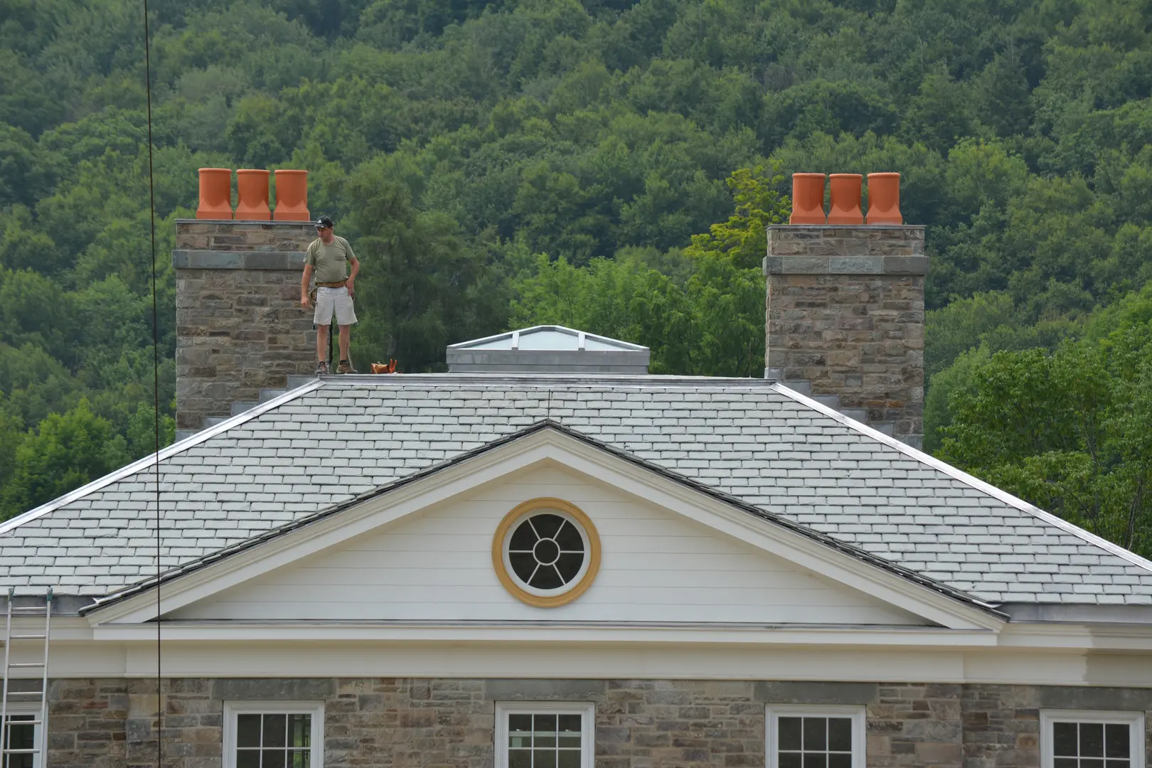 A man standing on top of a building near some trees.