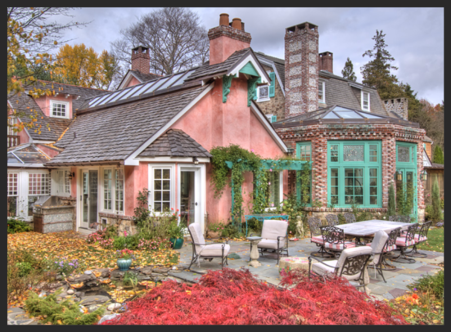 A pink house with green shutters and red leaves.