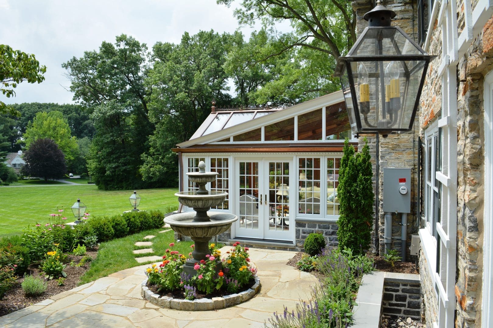 A garden with a fountain and a house