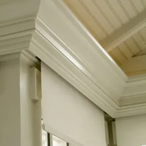 A white roller shade in the corner of a room.