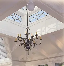 A chandelier in the middle of a room with a skylight.
