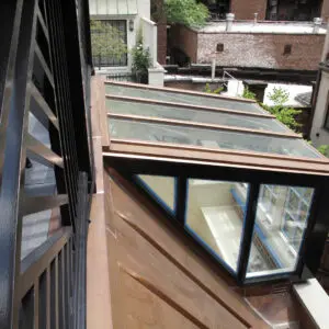 A wooden deck with a glass roof and a window.