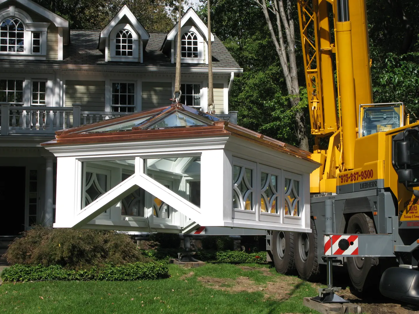 A crane is lifting a house on the ground.