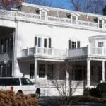 A white van parked in front of a large house.