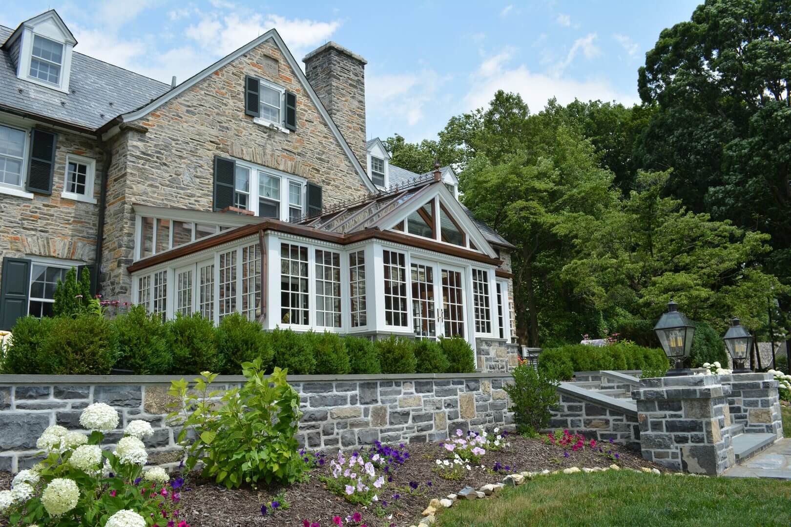 A stone house with flowers in front of it.