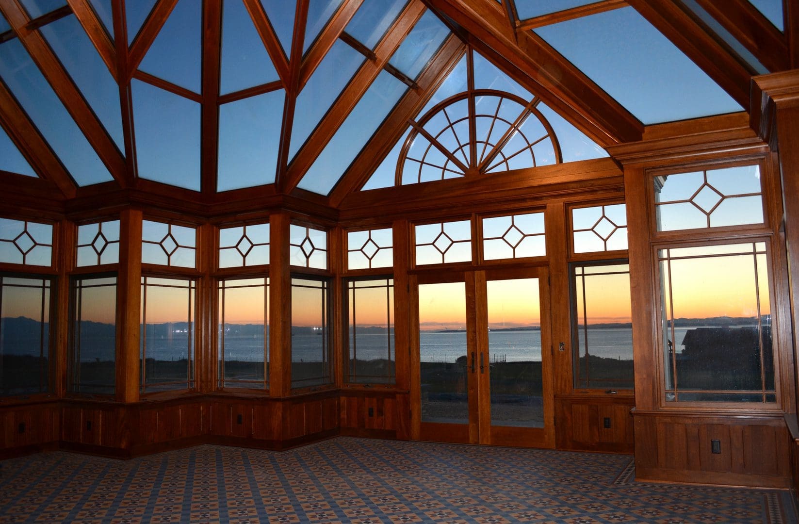 A room with many windows and doors overlooking the ocean.
