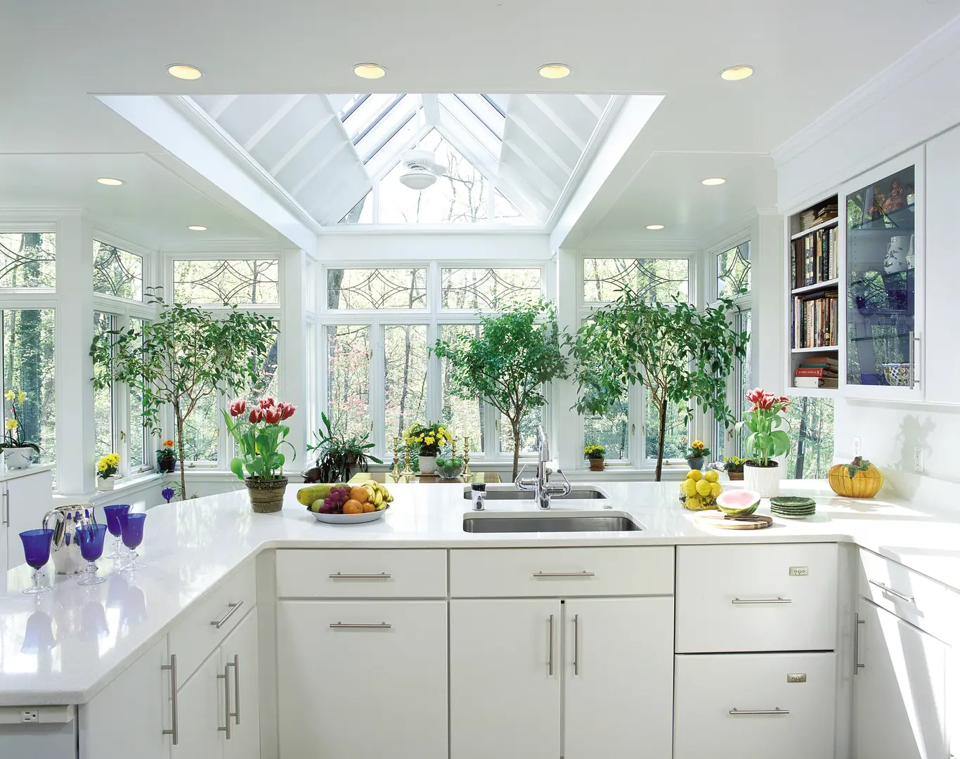 A kitchen with white cabinets and plants in the window.