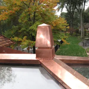 A copper roof with trees in the background