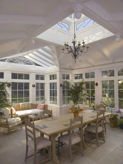 A dining room with a table and chairs, a chandelier and windows.