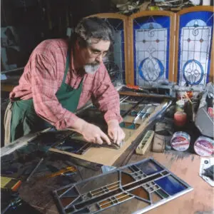 A man working on stained glass in his workshop.