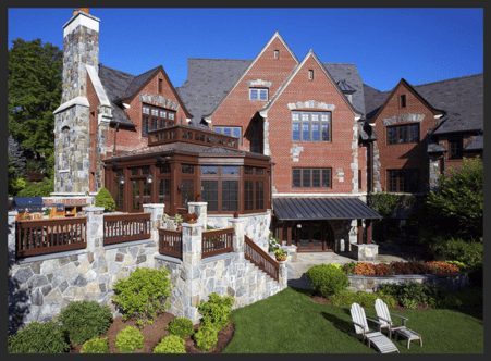 A large brick house with a patio and lawn furniture.