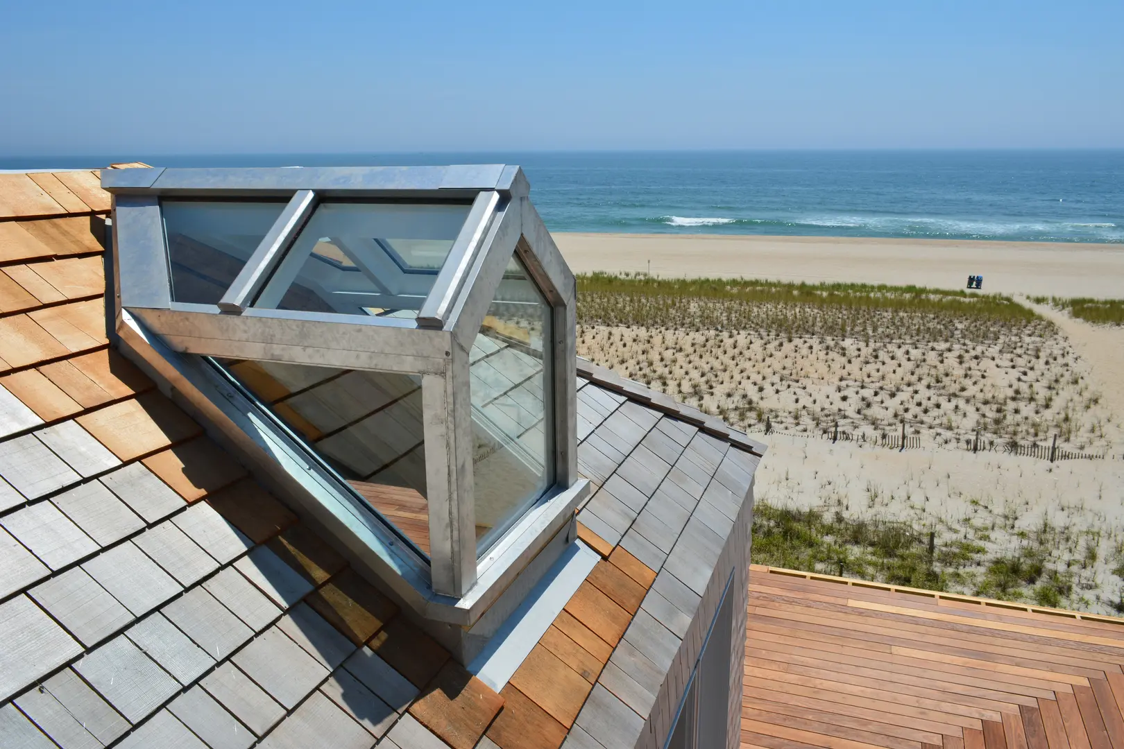 A roof with a glass window overlooking the beach.
