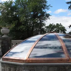 A large dome with copper trim on top of a stone wall.