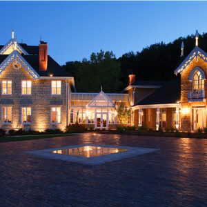 A large mansion with lights on the outside of it.