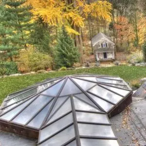 A glass roof in the middle of a garden.