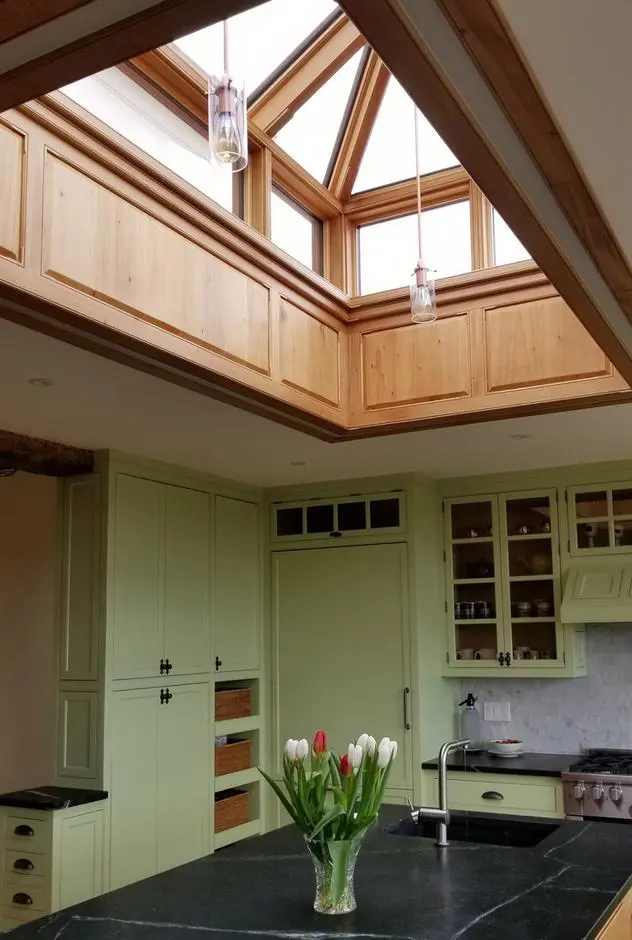 A kitchen with a large skylight and wooden cabinets.