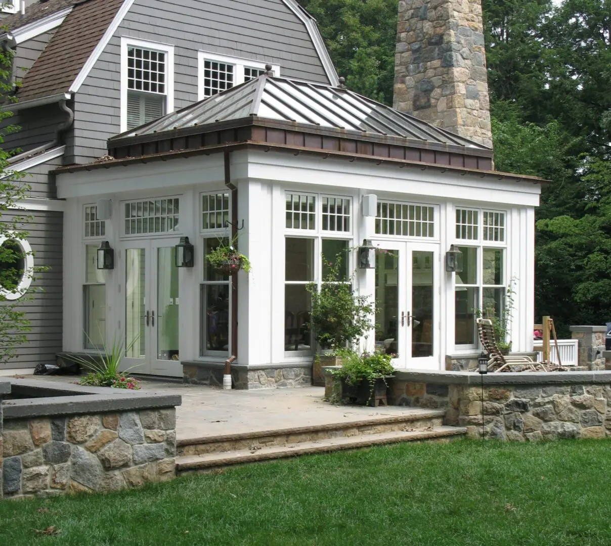 A large white house with stone walls and a patio.